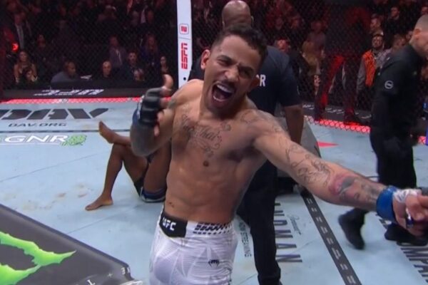 Tattooed UFC fighter Carlos Prates shouts and celebrates his victory inside the octagon after a fight.