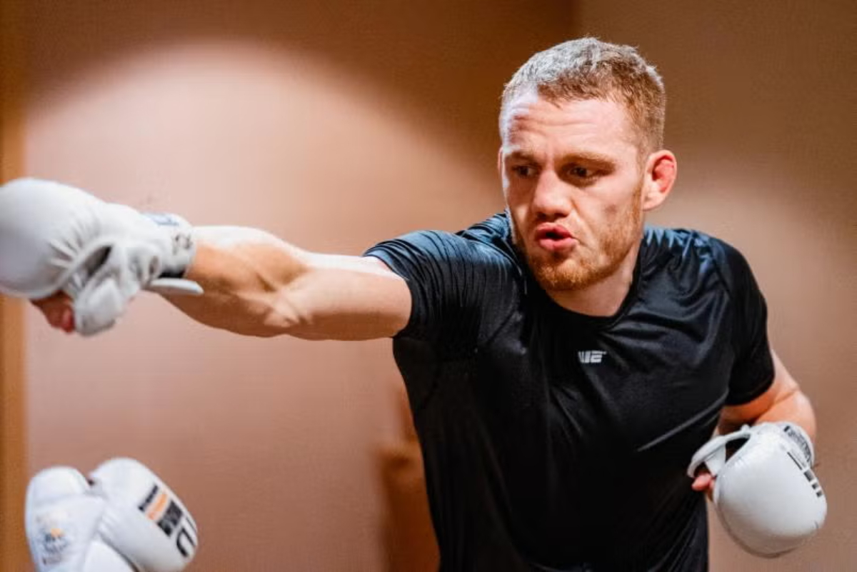 UFC fighter Jack Della Maddalena throws a punch while training, wearing a black shirt and white boxing gloves.