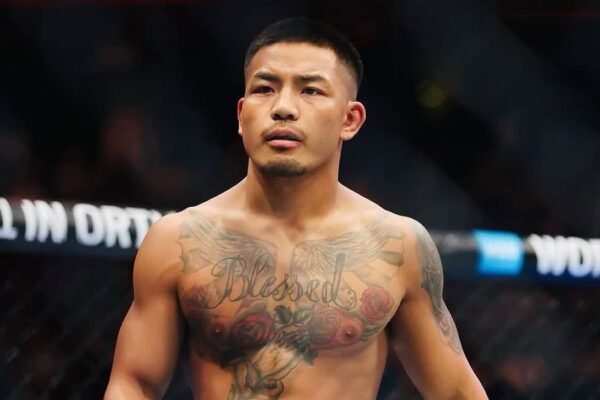 Close-up do lutador do UFC Joshua Van no octógono, exibindo sua tatuagem "Blessed" no peito.