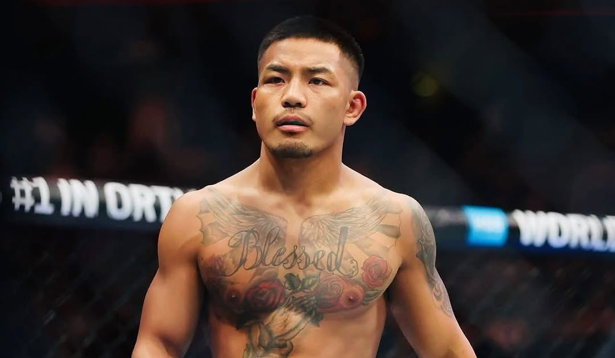 Close-up do lutador do UFC Joshua Van no octógono, exibindo sua tatuagem "Blessed" no peito.