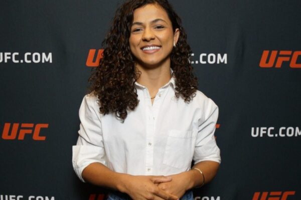 A lutadora do UFC, Natalia Silva, posa sorrindo com uma camisa branca durante evento para a imprensa.