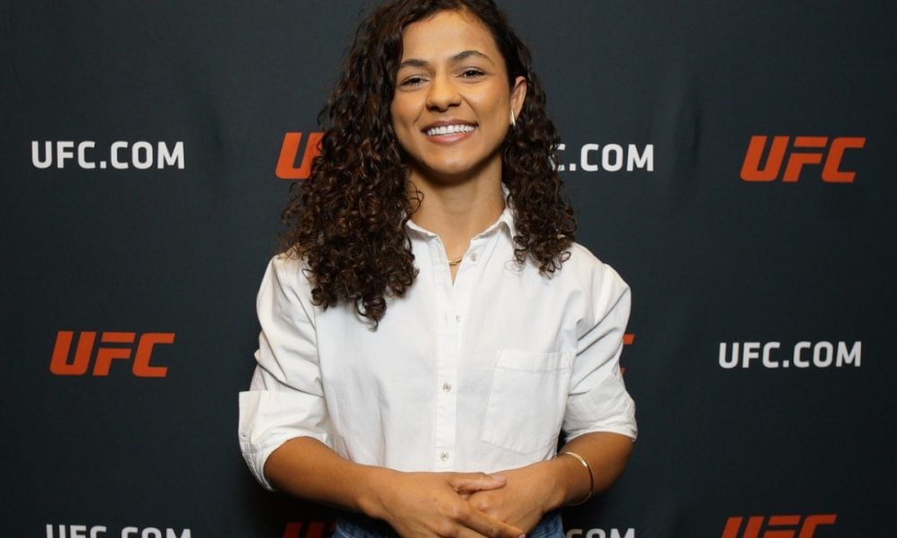 A lutadora do UFC, Natalia Silva, posa sorrindo com uma camisa branca durante evento para a imprensa.