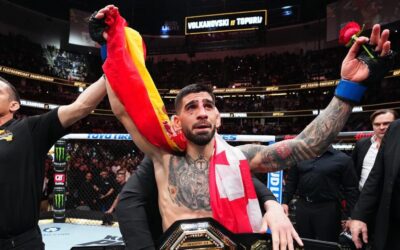 Ilia Topuria, campeão do UFC, comemora emocionado com o cinturão e as bandeiras da Espanha e Geórgia.