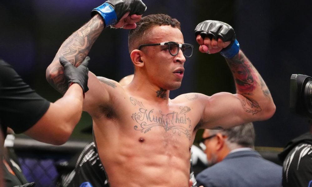 UFC fighter Carlos Prates celebrates a win, flexing his tattooed arms and wearing his signature glasses inside the octagon.
