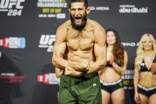 A bearded Khamzat Chimaev roars and flexes his muscular physique on stage at the UFC 294 weigh-in.