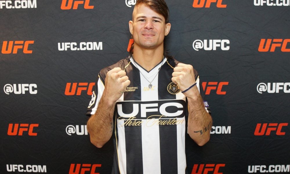 O lutador do UFC Diego Lopes posa com os punhos cerrados, vestindo uma camisa listrada preta e branca.