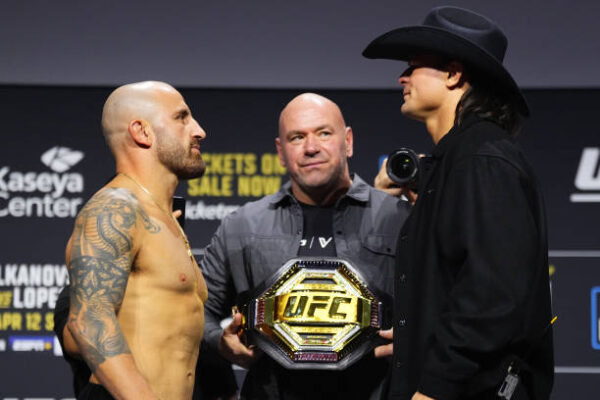 Dois lutadores do UFC se encaram com Dana White ao centro, segurando o cinturão de campeão.