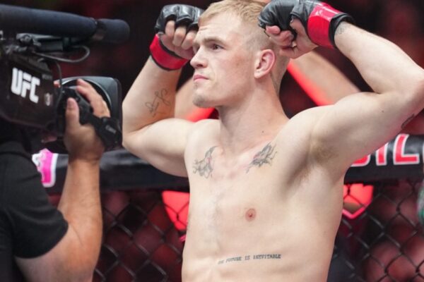 O lutador do UFC Ian Machado Garry posa no octógono, flexionando os braços e mostrando suas tatuagens.