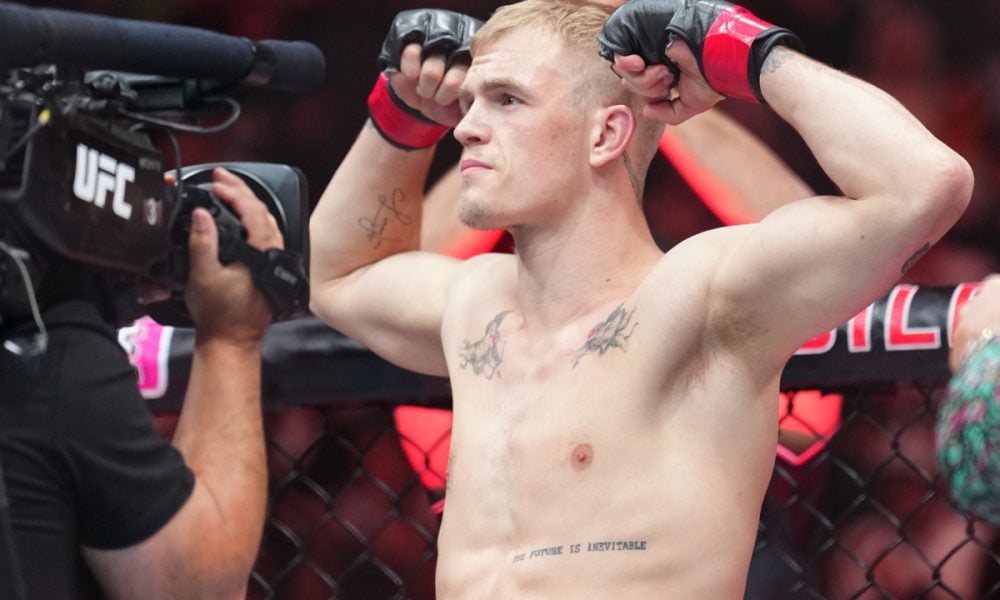 O lutador do UFC Ian Machado Garry posa no octógono, flexionando os braços e mostrando suas tatuagens.