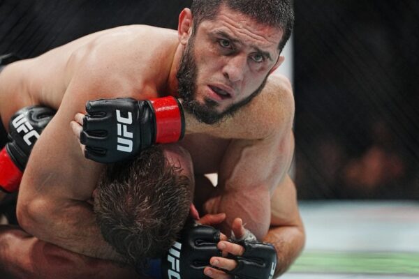 UFC fighter Islam Makhachev intensely applies a chokehold to his opponent on the ground during a match.