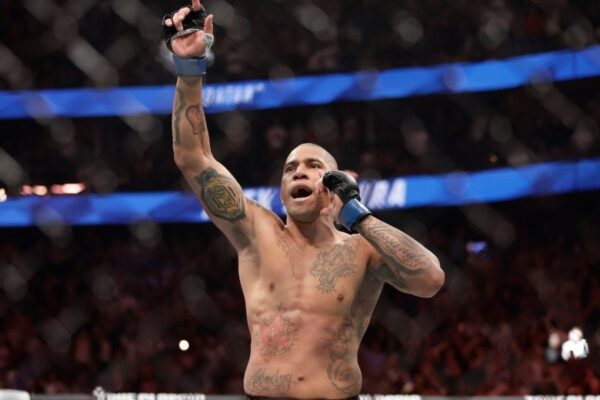 O lutador de MMA Alex Poatan Pereira, sem camisa, comemora vitória gritando com o braço erguido dentro do octógono.