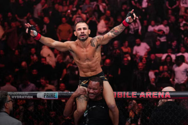 O lutador do UFC Alexandre Pantoja comemora a vitória nos ombros de seu técnico, com os braços erguidos.