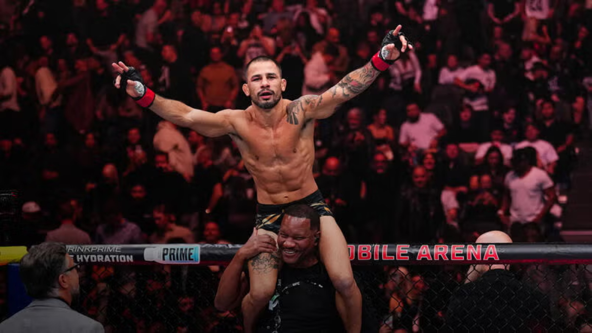 O lutador do UFC Alexandre Pantoja comemora a vitória nos ombros de seu técnico, com os braços erguidos.
